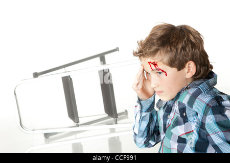 Little Boy con sanguinamento fronte seduto con scaletta in background Foto Stock