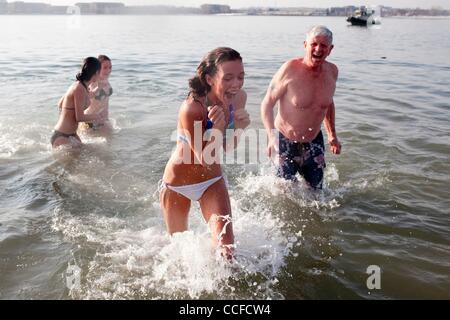 Jan 01, 2011 - Boston, Massachusetts, STATI UNITI - MEAGAN Johnson, 16, di Andover reagisce all'acqua fredda nel Dorchester Bay come suo nonno, TOM FUREY e sua sorella e cugina Kelly Johnson, 14 e LEA HART, sinistra, seguire il suo fuori di Dorchester Bay presso l Street Brownie nuotare. Il 2011 L Street Br Foto Stock