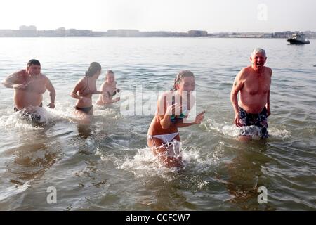 Jan 01, 2011 - Boston, Massachusetts, STATI UNITI - MEAGAN Johnson, 16, di Andover reagisce all'acqua fredda nel Dorchester Bay come suo nonno, TOM FUREY e sua sorella e cugina Kelly Johnson, 14 e LEA HART, sinistra, seguire il suo fuori di Dorchester Bay presso l Street Brownie nuotare. Il 2011 L Street Br Foto Stock