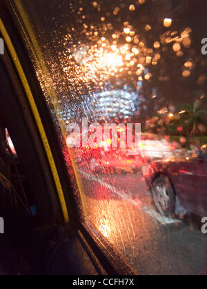 Vista offuscata del traffico della città dall'interno di un taxi a Singapore su di una notte piovosa Foto Stock