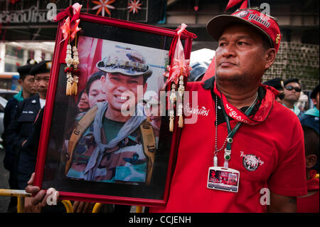 Dic. 19, 2010 - Bangkok Bangkok, Thailandia - maglietta rossa sostenitore portare una foto di Khattiya Sawasdipol, noto come 'eh Daeng'' un militray advisor di Camicie Rosse che è stato ucciso dietro la maglietta rossa encampment il 13 maggio 2010..Migliaia di ''Maglietta rossa'' anti-governo manifestanti si riuniranno presso la Financial Foto Stock