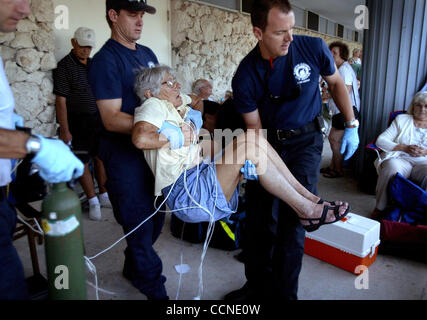 Set 25, 2004; Jensen Beach, Florida, Stati Uniti d'America; al di fuori di Jensen Beach Scuola Elementare, ortiche isola resident Fran Neubauer è aiutato da un ambulanza in attesa da Martin contea fuoco il personale di soccorso. Gli amici di attesa con Neubauer in linea (il ricovero non aveva ancora aperto) detto lei si lamentava di un corto Foto Stock