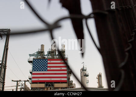 Oct 18, 2004; Long Beach, CA, Stati Uniti d'America; la Conoco philips raffineria di petrolio a Carson nr Long Beach in California con grandi stelle e strisce di bandiera degli Stati Uniti appeso accanto alla enorme chimmney fumaioli. La raffineria ha recinto di sicurezza con filo spinato filo spinato intorno ad esso. La sicurezza è stata aumentata a refinerys attraverso Foto Stock