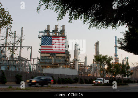 Oct 18, 2004; Long Beach, CA, Stati Uniti d'America; la Conoco philips raffineria di petrolio a Carson nr Long Beach in California con grandi stelle e strisce di bandiera degli Stati Uniti appeso accanto alla enorme chimmney fumaioli. La raffineria ha recinto di sicurezza con filo spinato filo spinato intorno ad esso. La sicurezza è stata aumentata a refinerys attraverso Foto Stock