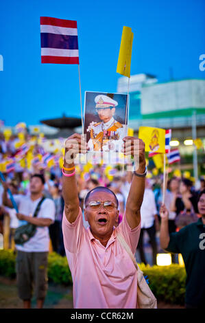 Un Pro-sostenitori del governo contiene un ritratto di Re Tailandese Bhumibol Adulyadej lungo con Royal Thai e bandiere durante un rally per mostrare il loro sostegno per il governo thailandese al Monumento della Vittoria. Governo anti-Camicie Rosse leader hanno accettato l'offerta dal Primo ministro tailandese Abhisit Vejjajiva per sciogliere il Foto Stock