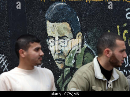 Apr 21, 2010 - Gaza City, nella Striscia di Gaza - palestinesi sedersi davanti a un graffiti raffiguranti catturato soldato israeliano Gilad Shali dipinta da membri di Hamas nel campo profughi di Jabaliya nel nord della striscia di Gaza, 21 aprile 2010. Israele deportati di Ahmad Sabah 40-anno-vecchio prigioniero palestinese per i compressori GA Foto Stock