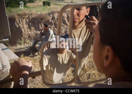 28 maggio 2010 - provincia di Badghis, Afghanistan - STATI UNITI Army Sgt. Arturo Alvarez del terzo plotone, Bravo batteria, 2° Battaglione, campo 321artiglieria, quarta brigata Team di combattimento, ottantaduesima Airborne Division, rade utilizzando lo specchio sulla porta di un veicolo MATV al posto di osservazione Barracuda vicino a Bala Murghab in Foto Stock