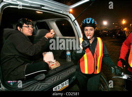 Novembre 19, 2008, Tijuana, Baja California, Messico prima dell'inizio di un settimanale il mercoledì sera Ciclopista Tijuana sera in bicicletta in corrispondenza del punto di partenza in un parcheggio adiacente a Tijuana municipio ROCIO GONZALEZ, sinistro e amico LUPITA GUTIERREZ condividere la cena prima di avere sulle loro moto Foto Stock