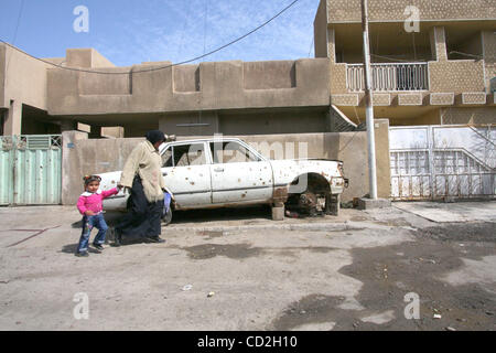 Mar 03, 2008 - quartiere di Dora, Baghdad, Iraq - una donna e un bambino sono a piedi nel quartiere di Dora di Bagdad, il passaggio di un auto con fori di proiettile. (Credito Immagine: © Simon Klingert/ZUMA Premere) Restrizioni: * Germania diritti * Foto Stock