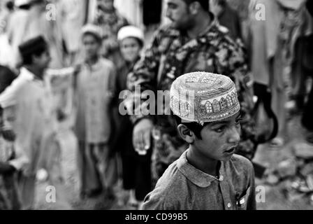 Un ragazzo afghano ascolta per anziani e l esercito nazionale afghano soldati parlare durante una shura o riunione, vicino Margah. Foto Stock