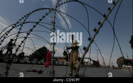 Un indiano poliziotti di guardia di fronte Razore filo durante un coprifuoco a Srinagar , la capitale estiva del Kashmir indiano il 2 / 7/ 2010 le autorità hanno esteso le restrizioni il coprifuoco a Srinagar intera città e alcuni dei suoi dintorni seguendo la HC è appello al popolo ad aderire al "Eidgah chall Foto Stock