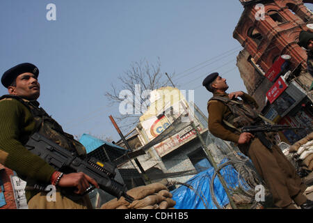 Un poliziotto indiano sta di guardia nella parte anteriore del Kashmir la torre dell orologio nello storico Lal Chowk (quadrato rosso) area davanti di un progetto di bandiera nazionale il sollevamento da India del principale partito d opposizione Bharatiya Janata Party (BJP) presso la torre sul giorno della Repubblica, a Srinagar,la capitale estiva del Kashmir indiano il 25 gennaio, 2011. Foto Stock