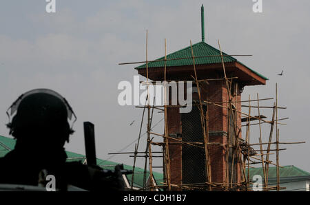 Un poliziotto indiano sta di guardia nella parte anteriore del Kashmir la torre dell orologio nello storico Lal Chowk (quadrato rosso) area davanti di un progetto di bandiera nazionale il sollevamento da India del principale partito d opposizione Bharatiya Janata Party (BJP) presso la torre sul giorno della Repubblica, a Srinagar,la capitale estiva del Kashmir indiano il 25 gennaio, 2011. Foto Stock