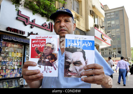 Un egiziano l'uomo guarda i libri e le riviste con un front page foto del deposto leader egiziano Hosni Mubarak il 25 maggio 2011, un giorno dopo il procuratore di Stato ha annunciato che il Presidente Mubarak e i suoi due figli dovrebbero affrontare un processo in un tribunale penale oltre le uccisioni di anti-regime manifestanti e la corruzione. Ph Foto Stock