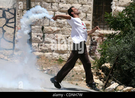 Un dimostrante getta indietro una lacrima bombola del gas sparati dalle forze israeliane durante scontri a seguito di una protesta contro l'espropriazione delle terre palestinesi, nel villaggio di Nabi Saleh, Israeliano-West Bank occupata, il 10 giugno 2011. Foto di Issam Rimawi Foto Stock