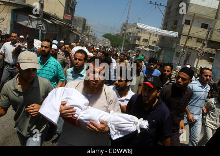 Agosto 19, 2011 - Rafah nella striscia di Gaza - un uomo palestinese porta il corpo di due-anno-vecchio ragazzo Malek Sha'at Durante il suo funerale a Rafah nel sud della striscia di Gaza. Un attacco aereo israeliano ha ucciso il leader di un'armata fazione palestinese, un tenente superiore, tre altri membri e Sha'a nel sud di ga Foto Stock