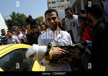 Un uomo palestinese porta il corpo di due-anno-vecchio ragazzo Islam Qreqa durante un funerale di Gaza City il 20 agosto 2011. Palestinesi detto almeno nove militanti sono morti in più israeliani, così come due bambini, uno di loro Islam Qreqa. Foto di Mohammed Asad Foto Stock