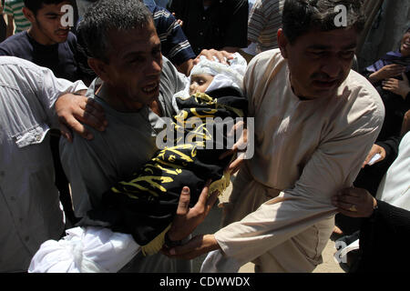 Un uomo palestinese porta il corpo di due-anno-vecchio ragazzo Islam Qreqa durante un funerale di Gaza City il 20 agosto 2011. Palestinesi detto almeno nove militanti sono morti in più israeliani, così come due bambini, uno di loro Islam Qreqa. Foto di Mohammed Asad Foto Stock