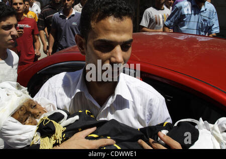 Un uomo palestinese porta il corpo di due-anno-vecchio ragazzo Islam Qreqa durante un funerale di Gaza City il 20 agosto 2011. Palestinesi detto almeno nove militanti sono morti in più israeliani, così come due bambini, uno di loro Islam Qreqa. Foto di Naaman Omar Foto Stock