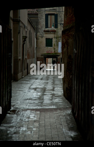 Una strada di Venezia con una profila la figura di una donna esce in corrispondenza della estremità lontana Foto Stock