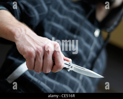 Il crimine di coltello. Maschio con cappuccio brandendo un coltello butterfly. Foto Stock