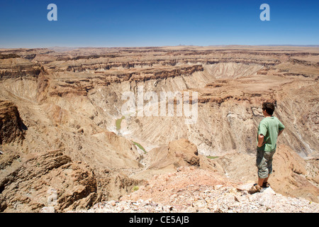 Un uomo sta guardando fuori attraverso il Fish River Canyon nel sud della Namibia. Foto Stock