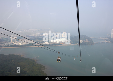 Guardando attraverso la finestra della cabina della cabinovia Ngong Ping 360 su Tung Chung bay e l'aeroporto internazionale dell'Isola di Lantau hong Foto Stock