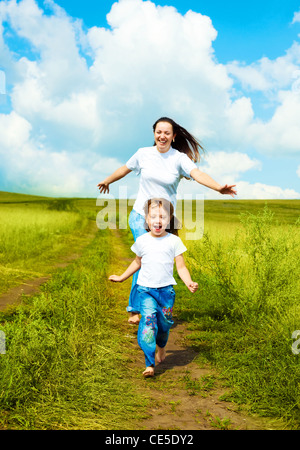 Giovane madre e la sua piccola figlia che corre lungo la strada all'aperto su un giorno di estate Foto Stock