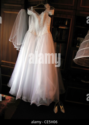 Pizzo bianco abito da sposa su hanger e scarpe Foto Stock