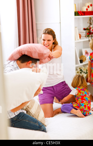 La famiglia felice avente un cuscino lotta nel letto Foto Stock