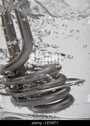 In eine Krug steht ein Tauchsieder und bringt das Wasser zum kochen | un immersione resiste stand in una tazza e è acqua bollente Foto Stock