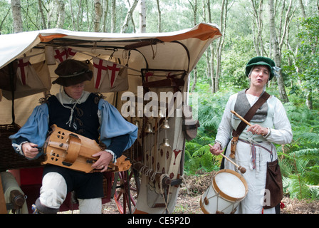 L uomo e la donna vestita come musicisti medievale di fronte ad una tenda con alberi in riproduzione in background organetto di barberia e tamburo Foto Stock