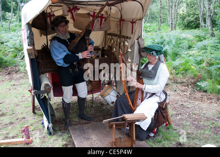 L uomo e la donna vestita come musicisti medievale di fronte ad una tenda con alberi in background la riproduzione di cornamuse e arpa Foto Stock