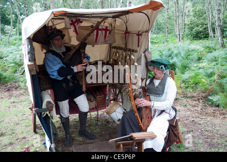 L uomo e la donna vestita come musicisti medievale di fronte ad una tenda con alberi in background la riproduzione di cornamuse e arpa Foto Stock