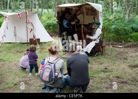 L uomo e la donna vestita come musicisti medievale di fronte ad una tenda la riproduzione di cornamuse e arpa guardato da giovane e bambini Foto Stock