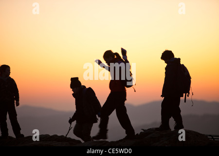 Un gruppo di bambini in età scolare su Orrest testa sopra Windermere al tramonto, nel distretto del lago, UK. Foto Stock