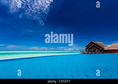 La piscina a sfioro sulla laguna tropicale con quasi il cielo blu chiaro Foto Stock