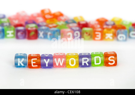 Testo parole chiave su cubi colorati su bianco. Casualmente disperse i cubi su sfondo Foto Stock