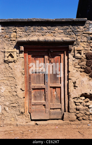 Chiusa la porta di legno su pietra muro di mattoni facciata della casa di villaggio Dwarka Bet Gujarat India Foto Stock