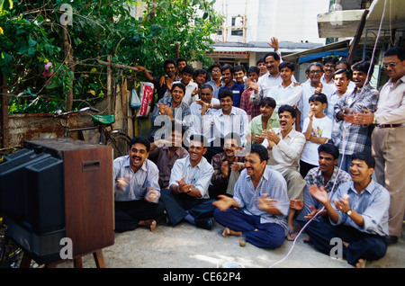 La folla di persone che applaudono felici di ridere edificio residenti a guardare sulla TV Coppa del Mondo di cricket tra India Pakistan 1999 Foto Stock