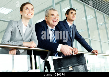 Tre persone di affari in ufficio in piedi da colonnine Foto Stock