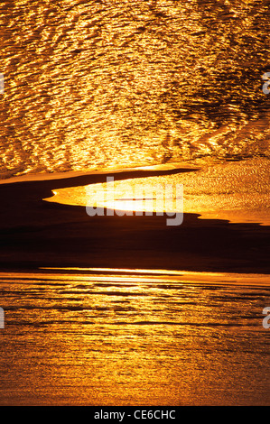 Golden scintillante acqua di mare e cielo rossastro al tramonto Foto Stock