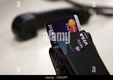 Carte di credito in un supporto con un ricevitore telefonico in background Foto Stock