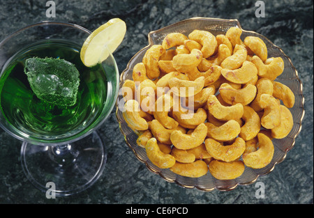 Noci di anacardi ; aromatizzate con Kesar ; in recipiente di vetro e bicchiere di succo di frutta di colore verde ; india ; asia Foto Stock