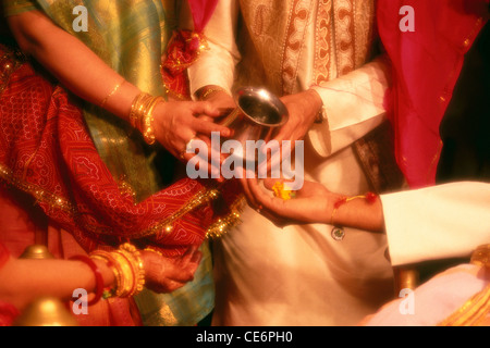 Cerimonia nuziale indiana con la sposa e lo sposo mani closeup versando acqua Santa ; India ; Asia Foto Stock