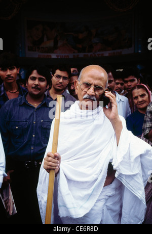 Uomo vestito come il Mahatma Gandhi parlando al telefono mobile India Foto Stock