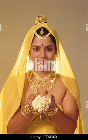 DAC 85217 : donna che indossa gioielli in oro collana schiave Orecchini gioielli di fronte offrendo mogra bianco fiori india
