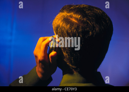 NVM 84048 : Sud Asiatico uomo indiano imprenditore schienale posteriore parlando cordless telefono mobile sfondo blu signor#201 Foto Stock