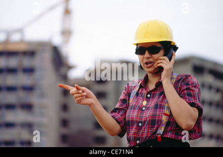 PRG 84182 : Costruzione lavorazione Donna che parla del modello di telefono cellulare rilasciato Foto Stock