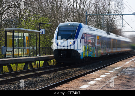 Borgo treno che passa alla piccola stazione il giorno di inizio della primavera Foto Stock